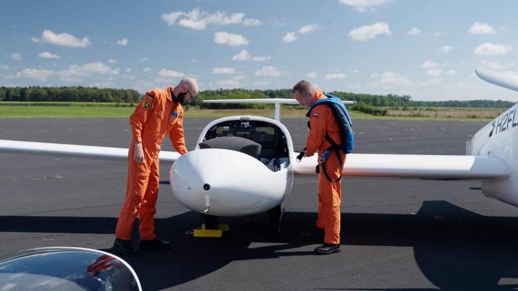 Zwei H2FLY-Mitarbeiter stehen neben einem kleinen Flugzeug auf einem Flugplatz