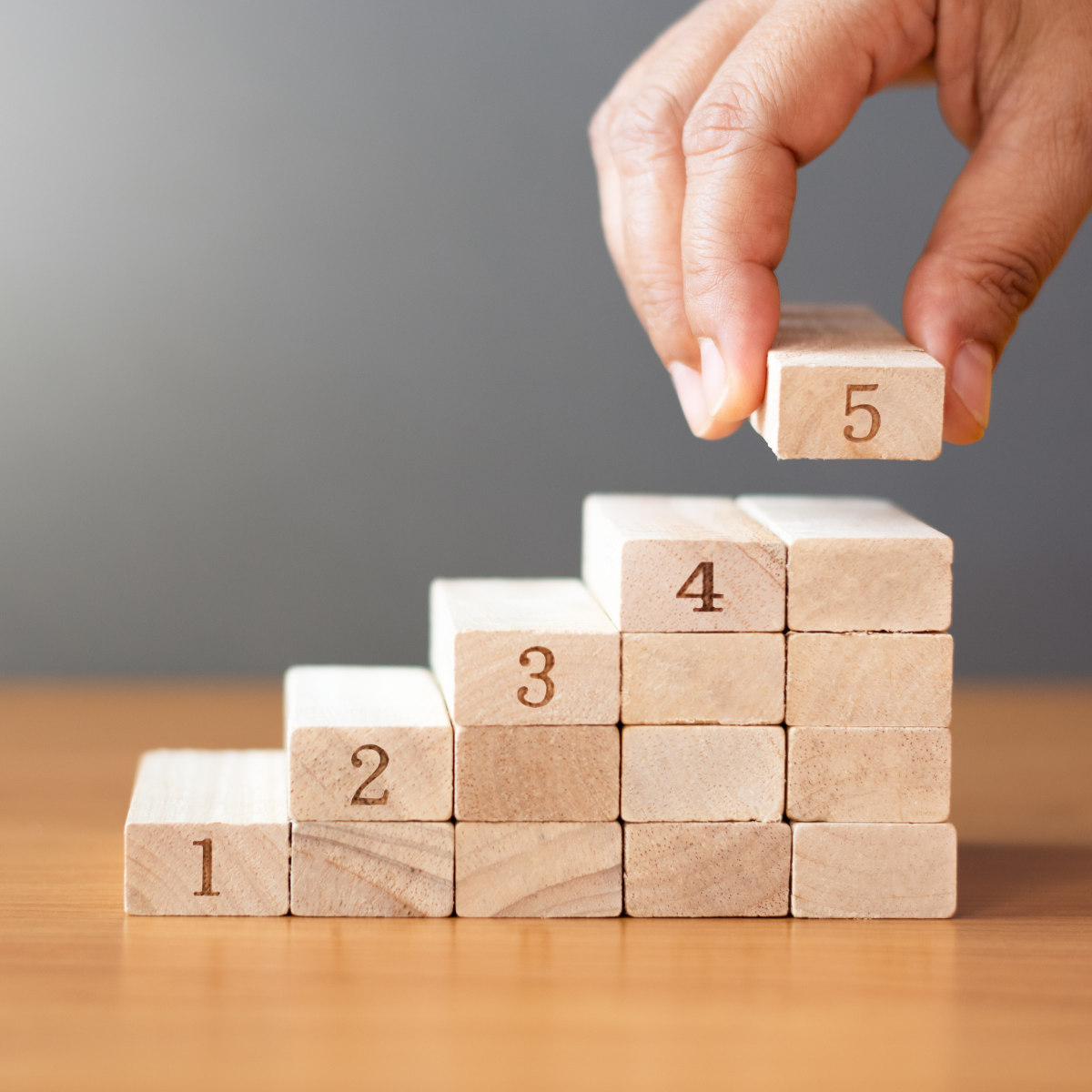 Zur Treppe gestapelte Bauklötze, nummeriert 1-5