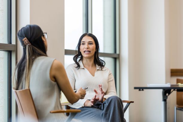 Foto zweier Frauen, die sich auf Stühlen gegenübersitzen unterhalten. Bild: iStock/SDI Productions